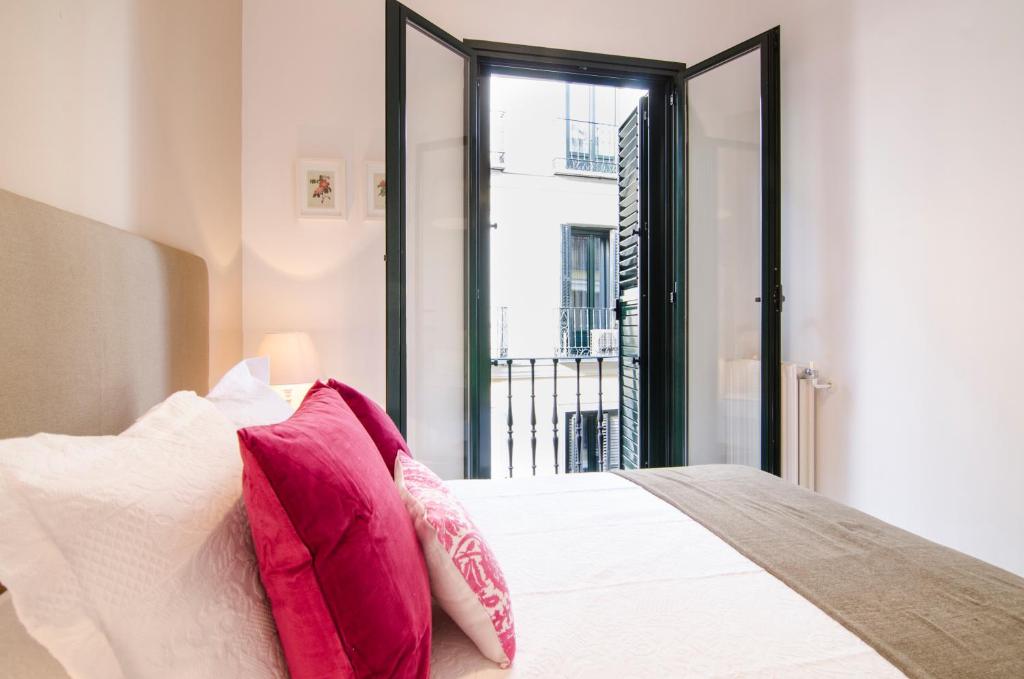 1 dormitorio con cama blanca y almohadas rosas en Cruz Apartment, en Madrid