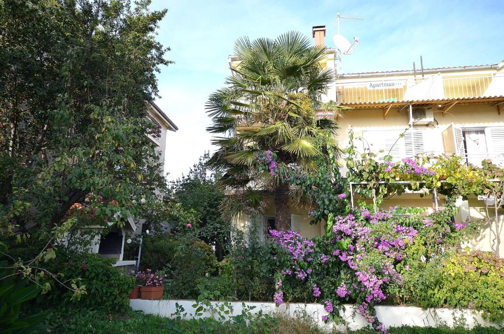 a house with a palm tree and flowers in front of it at Apartments Miriam Srima in Vodice