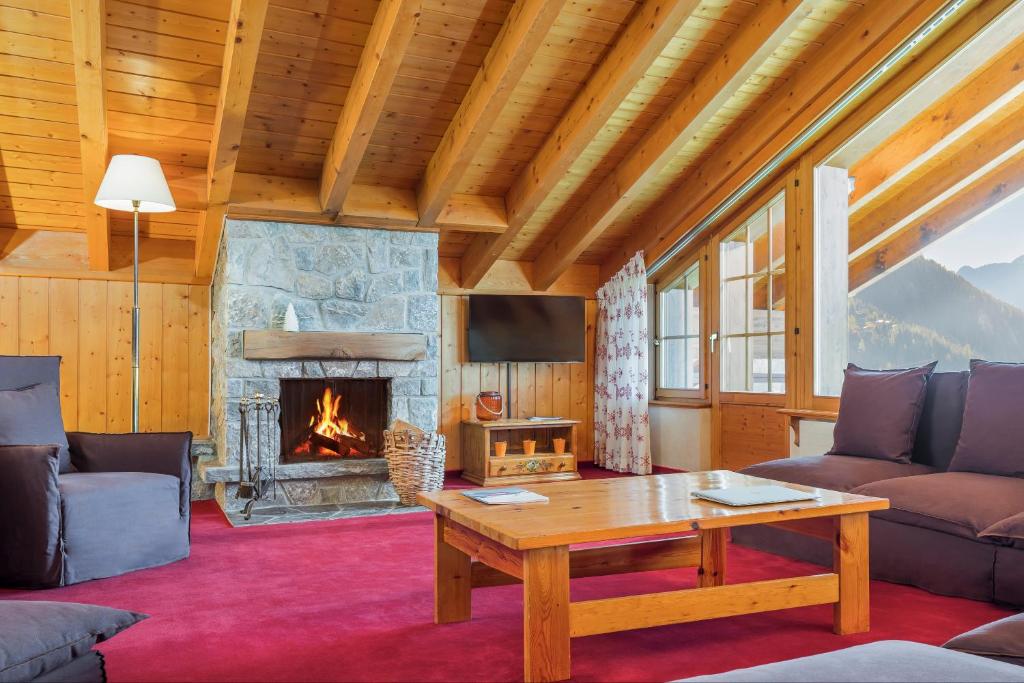 a living room with a fireplace and a table at Hotel Montpelier in Verbier