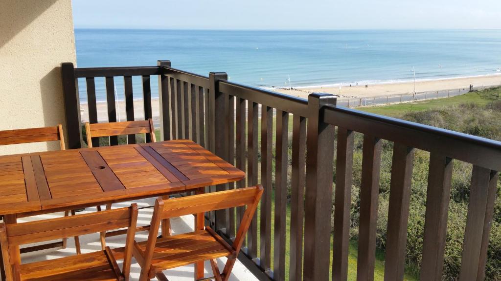 - une table et des chaises en bois sur un balcon donnant sur la plage dans l'établissement Magnifique vue Mer et Forêt, à Cabourg