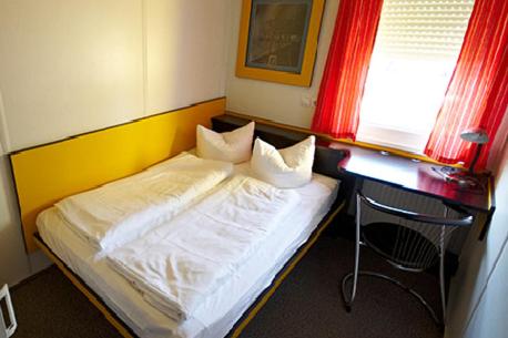 a bedroom with a bed and a desk with a chair at Motel Pelikan in Dettelbach