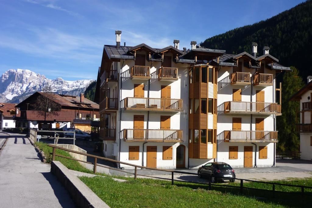 a large building with balconies and snow covered mountains at Casa Stella in Falcade
