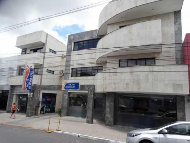 a building on a street with a car parked in front at Hotel Rodrigues in Garanhuns