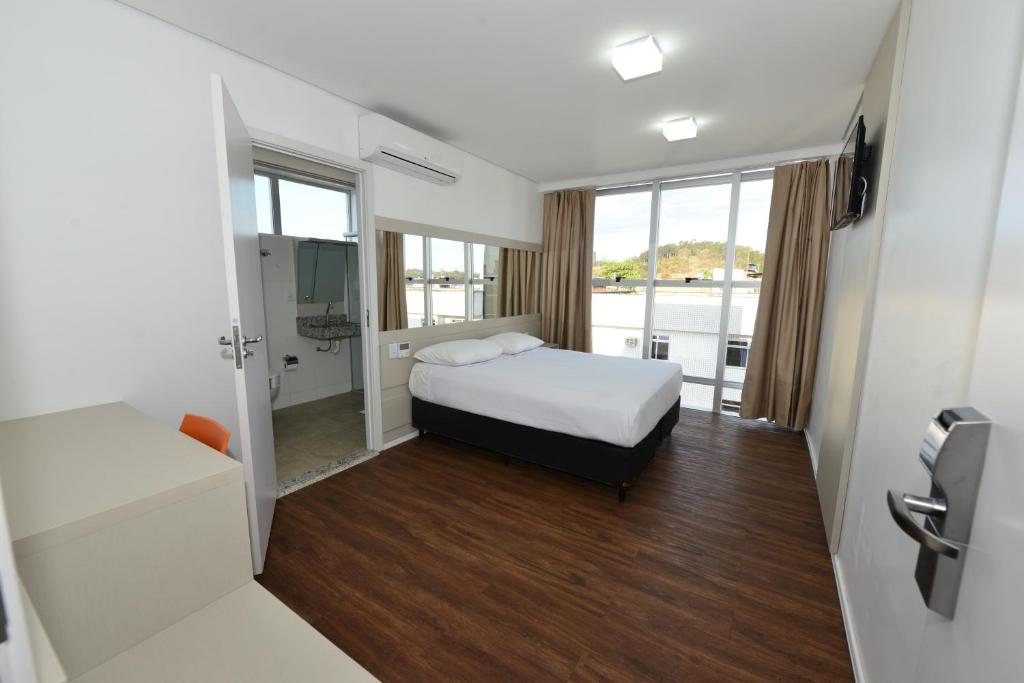 Habitación pequeña con cama y baño. en Hotel Panorama Economic, en Ipatinga