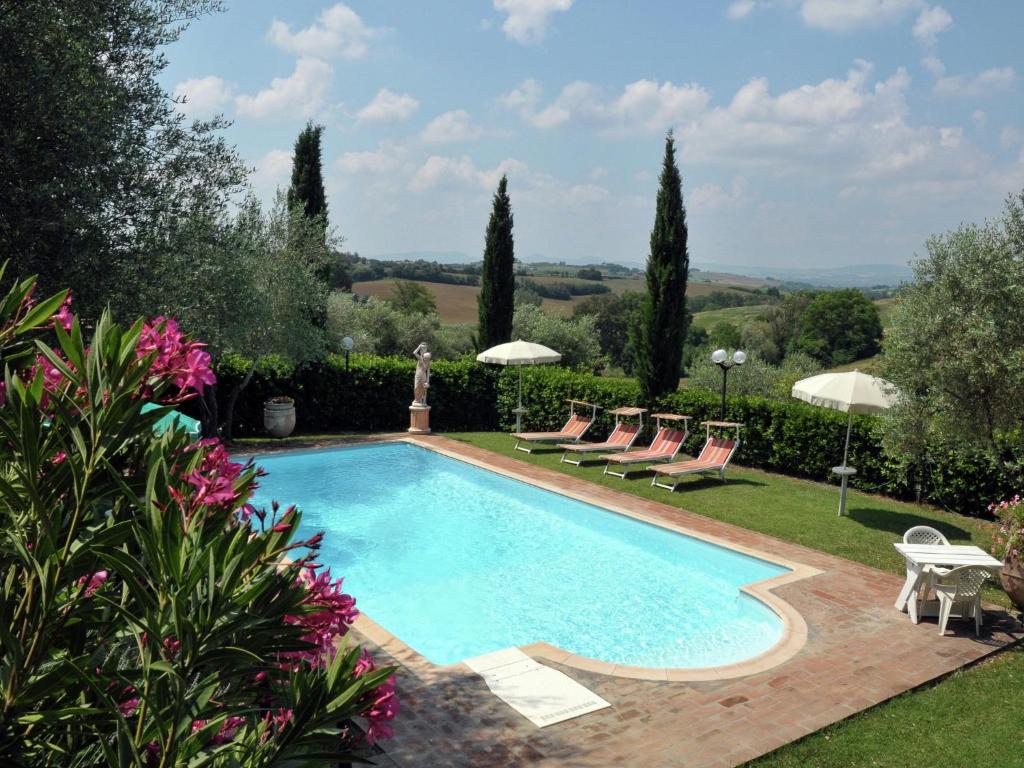 una piscina en un jardín con sillas y sombrillas en Belvilla by OYO Casale le Capanne, en Cortona