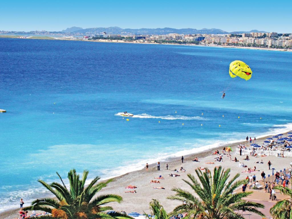 a group of people on a beach flying kites at Hôtel Le Royal Promenade des Anglais in Nice