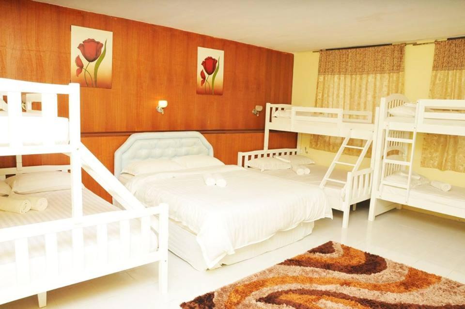 a bedroom with white bunk beds and a rug at Zeala Asmara Motel in Kuah