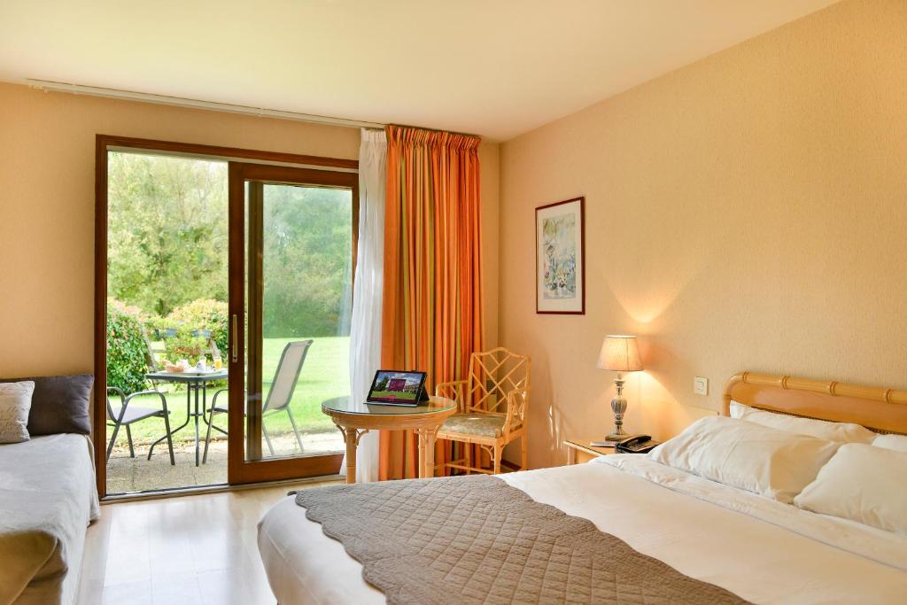 
a hotel room with a bed, chair, and a window at Logis Le Relais De Pouilly in Pouilly-sur-Loire
