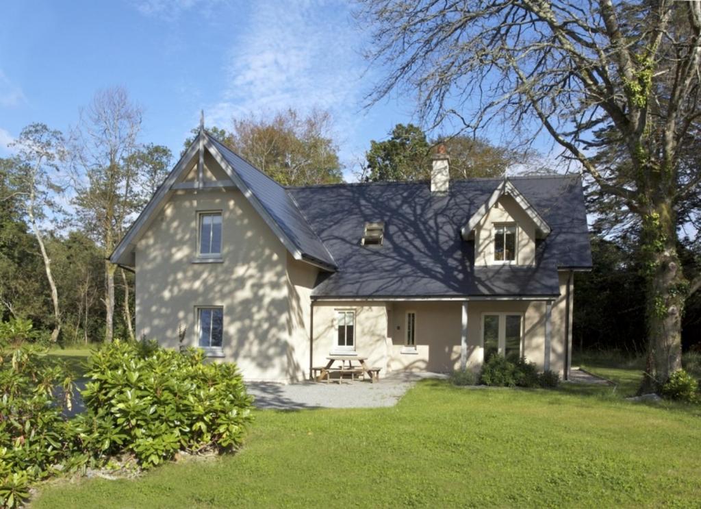 a large white house with a black roof at Dunkerron Woods Holiday Homes in Kenmare