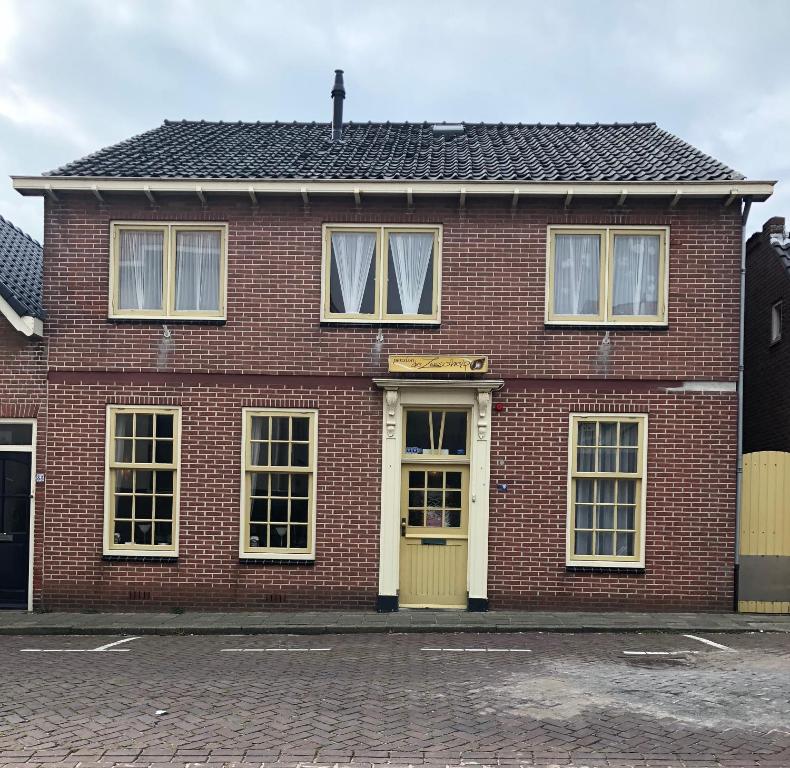 un bâtiment en briques rouges avec une porte jaune dans l'établissement Pension de Zeeschelp, à Domburg