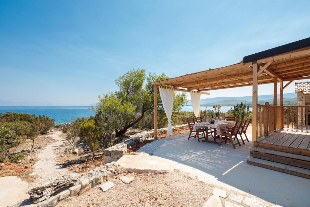 taras ze stołem i krzesłami i widokiem na ocean w obiekcie Private Bay Residence w mieście Vrboska
