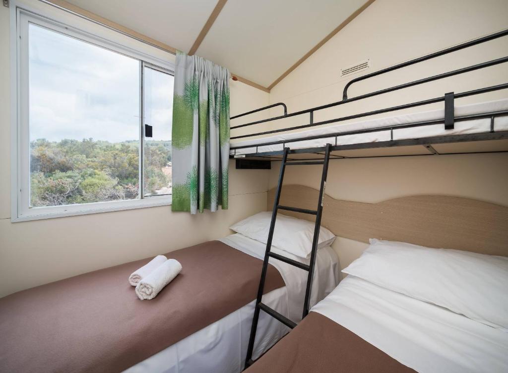 sypialnia z dwoma łóżkami piętrowymi i oknem w obiekcie Private Bay Residence w mieście Vrboska