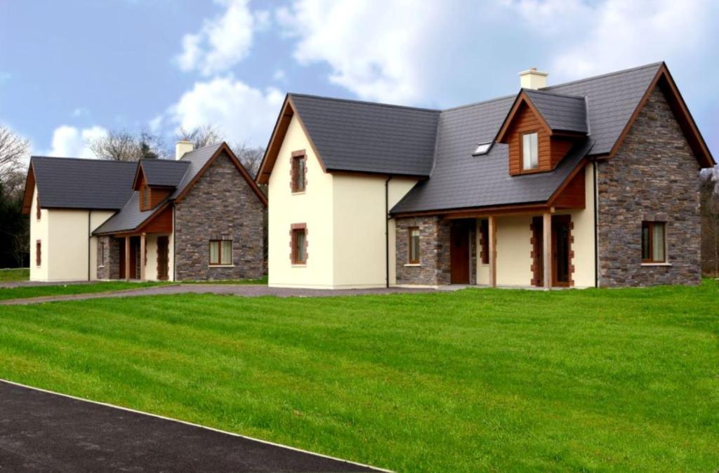 a house with a black roof and green grass at Ardnagashel Woods in Bantry