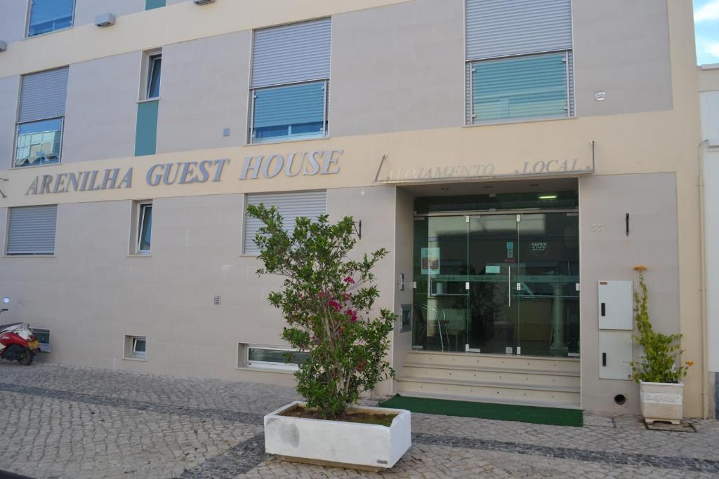 een wit gebouw met een boom ervoor bij Arenilha Guest House in Vila Real de Santo António