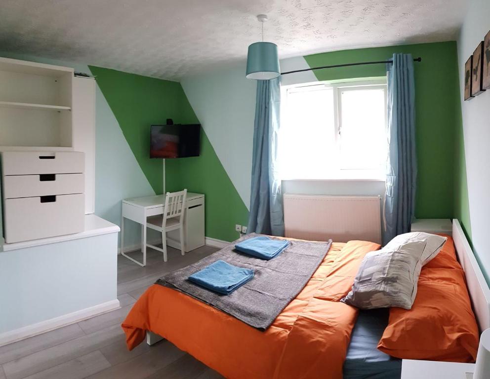 een slaapkamer met groene muren en een oranje bed bij Columbine, Thetford, 2BR House in Thetford