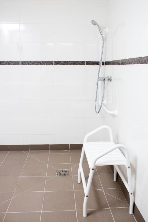 a shower and a white chair in a bathroom at Ace Hôtel Caen Nord Mémorial in Caen