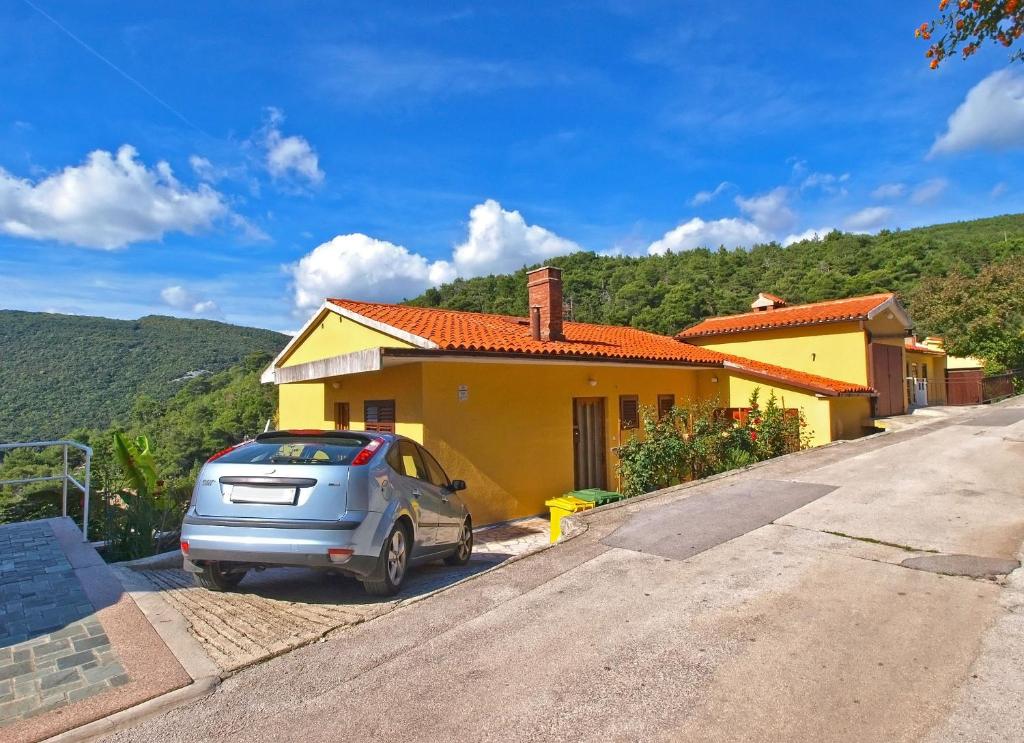 un coche aparcado frente a una casa amarilla en Apartments Boris 154, en Rabac