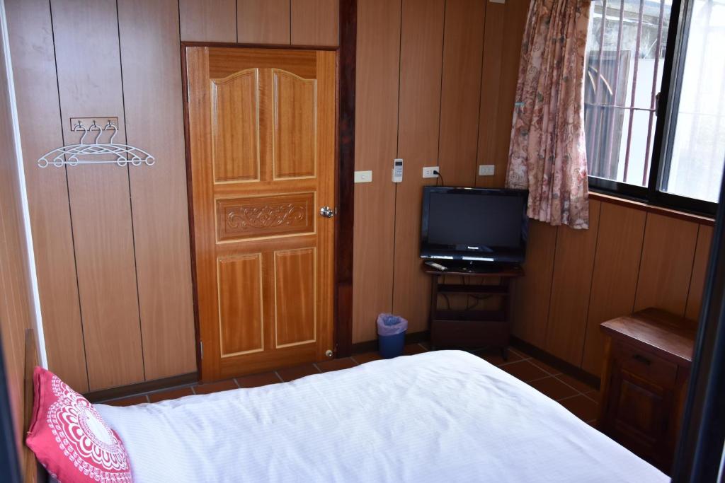 a bedroom with a bed and a tv and a door at Shi-Jia B&amp;B in Jiufen