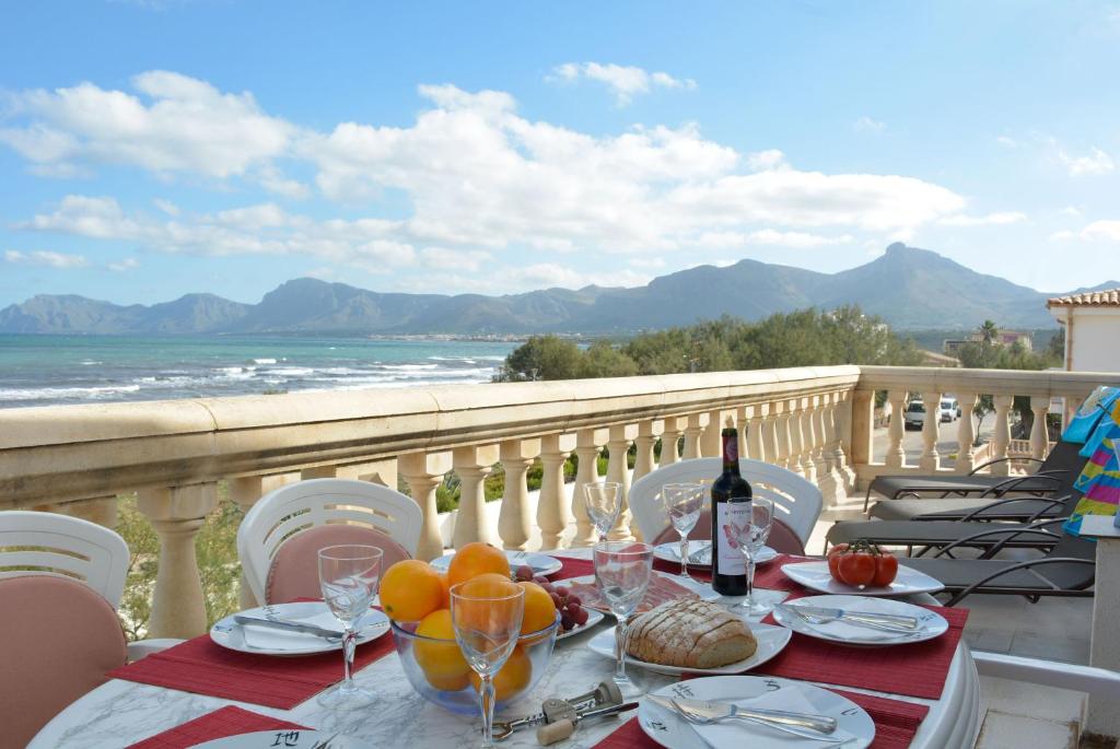 a table with food and wine on a balcony with the ocean at Front Line Beach Apartment in Son Serra in Son Serra de Marina