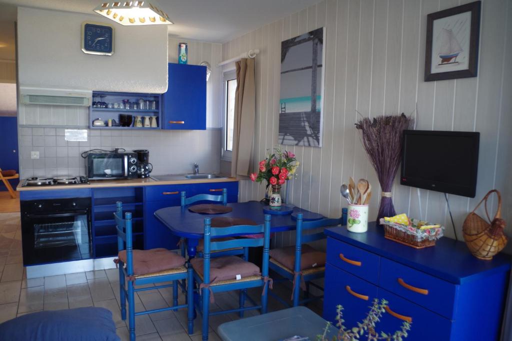 Le Ker Bleu في بيرو جييريك: مطبخ مع دواليب زرقاء وطاولة مع كراسي