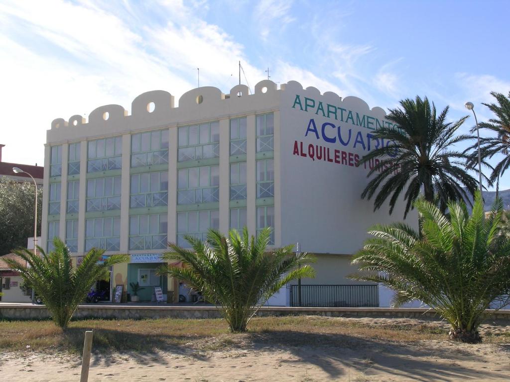 a large building with palm trees in front of it at Apartamentos Acuario in Denia
