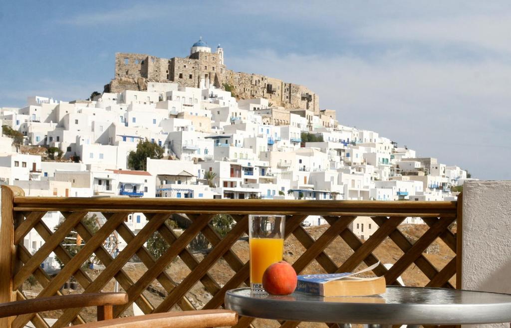 una mesa con un vaso de zumo de naranja en un balcón con una montaña en Atlantic, en Astipalea