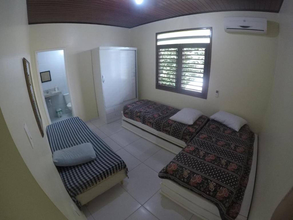 a small room with two beds and a window at Praia Barra de São Miguel in Barra de São Miguel