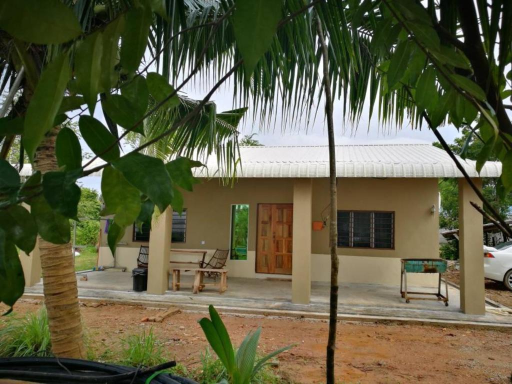 a house with a table and chairs in front of it at Homestay Pulau Langkawi in Pantai Cenang