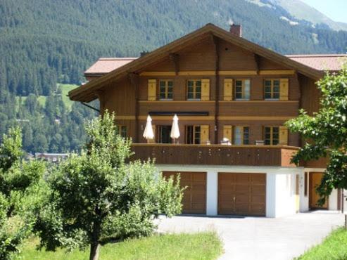 une grande maison en bois avec un garage dans l'établissement Chalet Studen, à Grindelwald