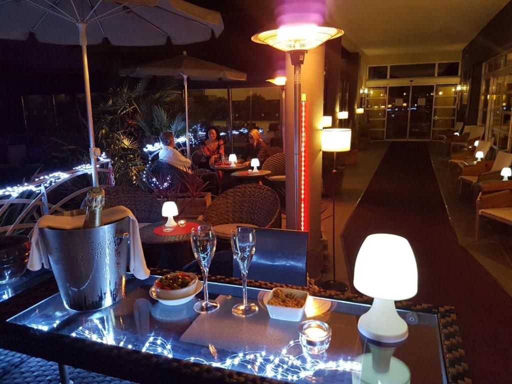 a restaurant with a table with wine glasses and lights at Logis Hôtel La Fauceille in Perpignan