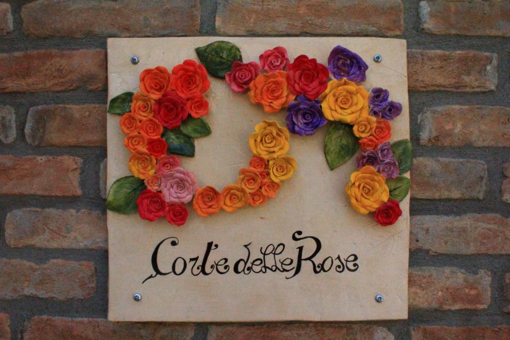 a sign with flowers on a brick wall at Corte Delle Rose in Voghera