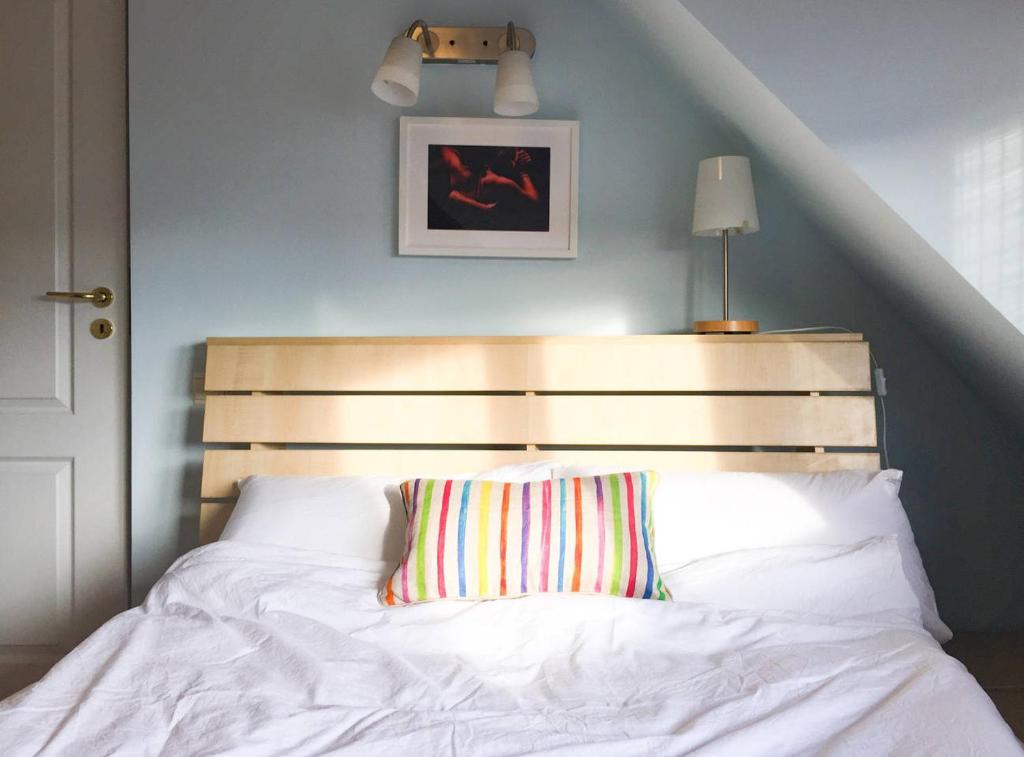 a bed with a wooden headboard and a striped pillow at Cozy Flat in Villa Near Old Town in Bucharest