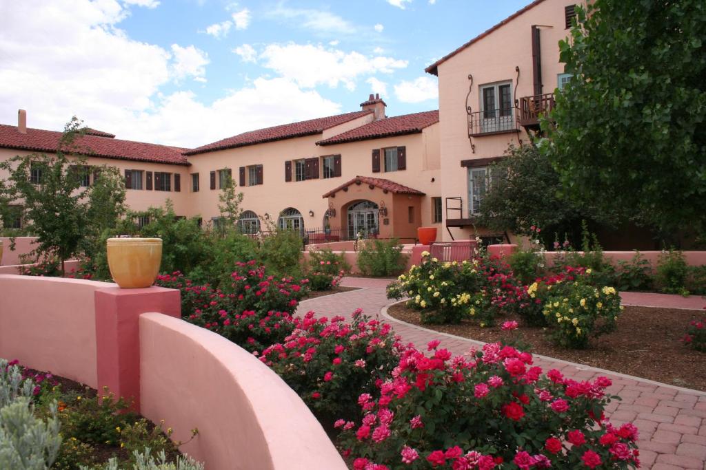 a large building with a patio with flowers in front of it at La Posada Hotel and Gardens in Winslow