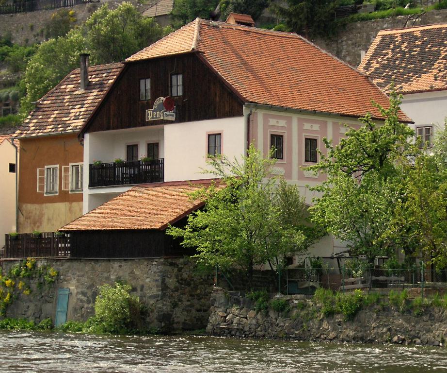 Pension Plešivecká 119 في تشيسكي كروملوف: مبنى على جانب نهر به بيوت