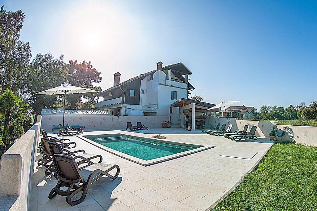 a swimming pool with chairs and a house at Villa Paolija in Novigrad Istria