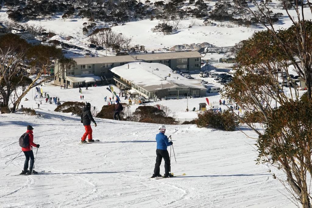 un groupe de personnes skier sur une piste enneigée dans l'établissement Smiggins Hotel & Chalet Apartments, à Perisher Valley