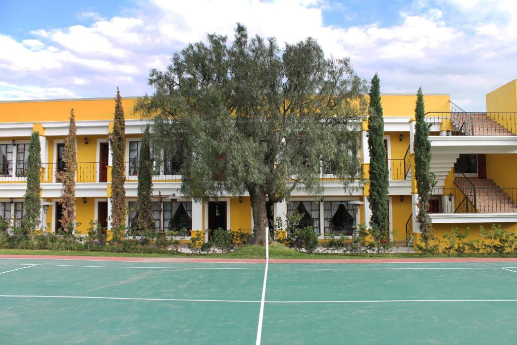 un court de tennis en face d'un bâtiment dans l'établissement Quinta Huizache, à Santa María Nopaltepec