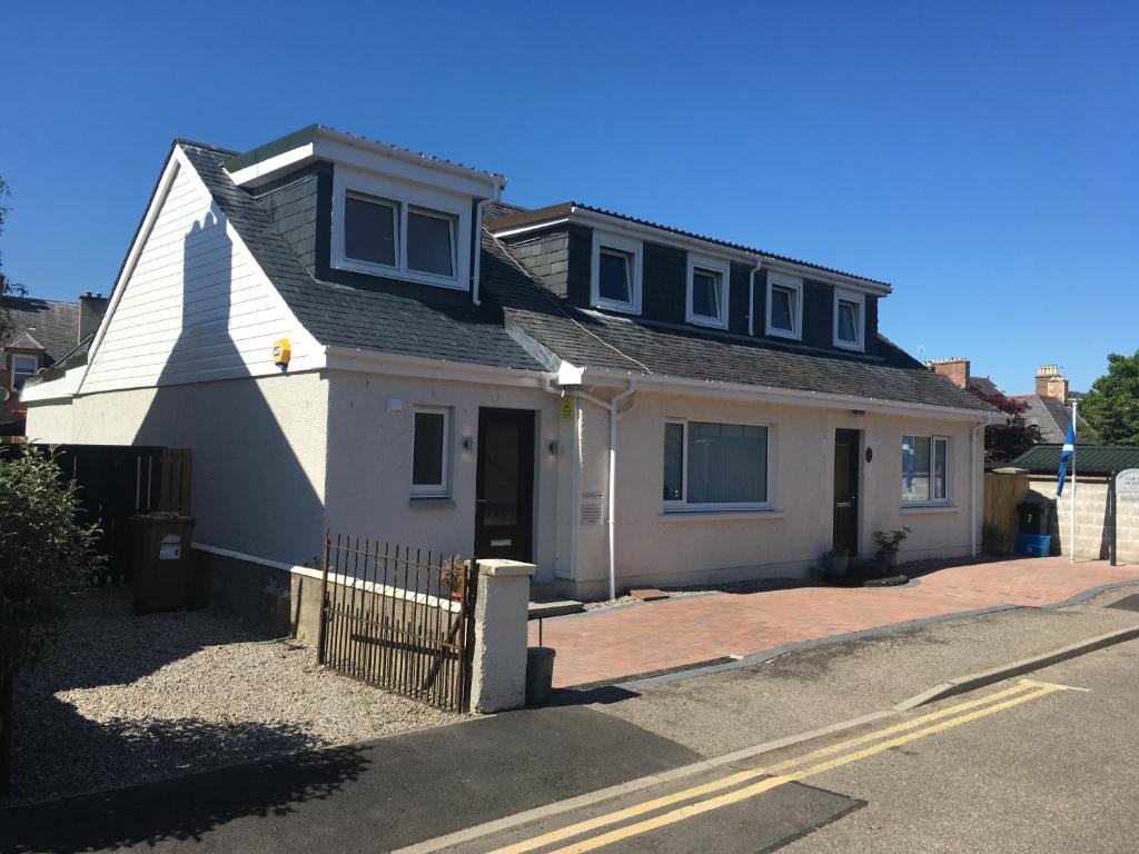 a white house with a black roof on a street at Silverstrands in Inverness