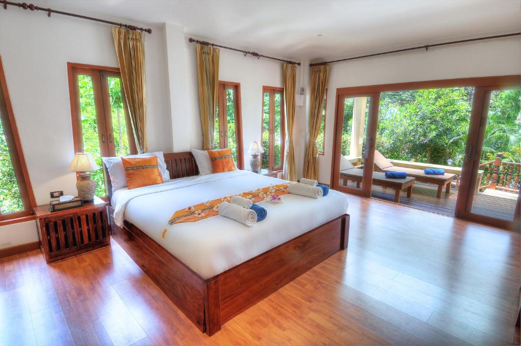 a bedroom with a large bed in a room with windows at Khanom Hill Resort in Khanom