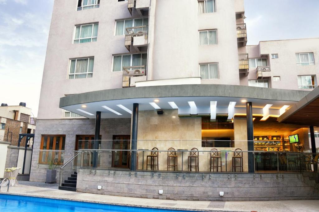 a hotel with a swimming pool in front of a building at The Zehneria By Sarovar Portico India in Nairobi