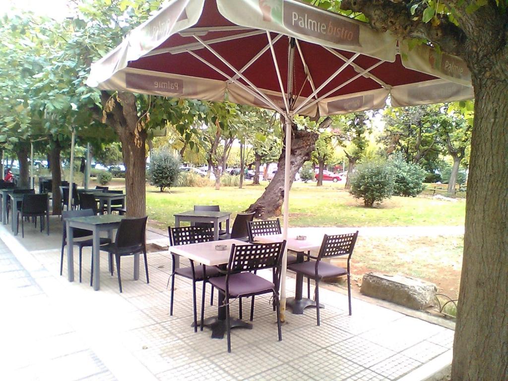 a patio with tables and chairs under an umbrella at Tranquil Central Apt, behind Athens Caravel Area in Athens
