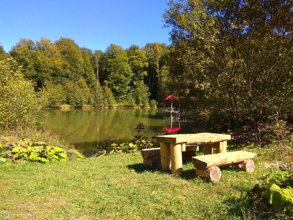 a picnic table in front of a lake with a red umbrella at Pihtoviy Bor Hotel in Dakhovskaya