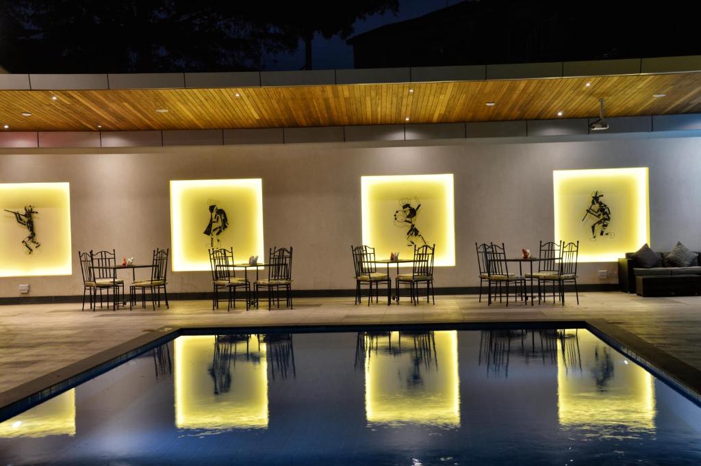 una habitación con sillas y mesas y una piscina en The Zehneria Hotel, en Nairobi