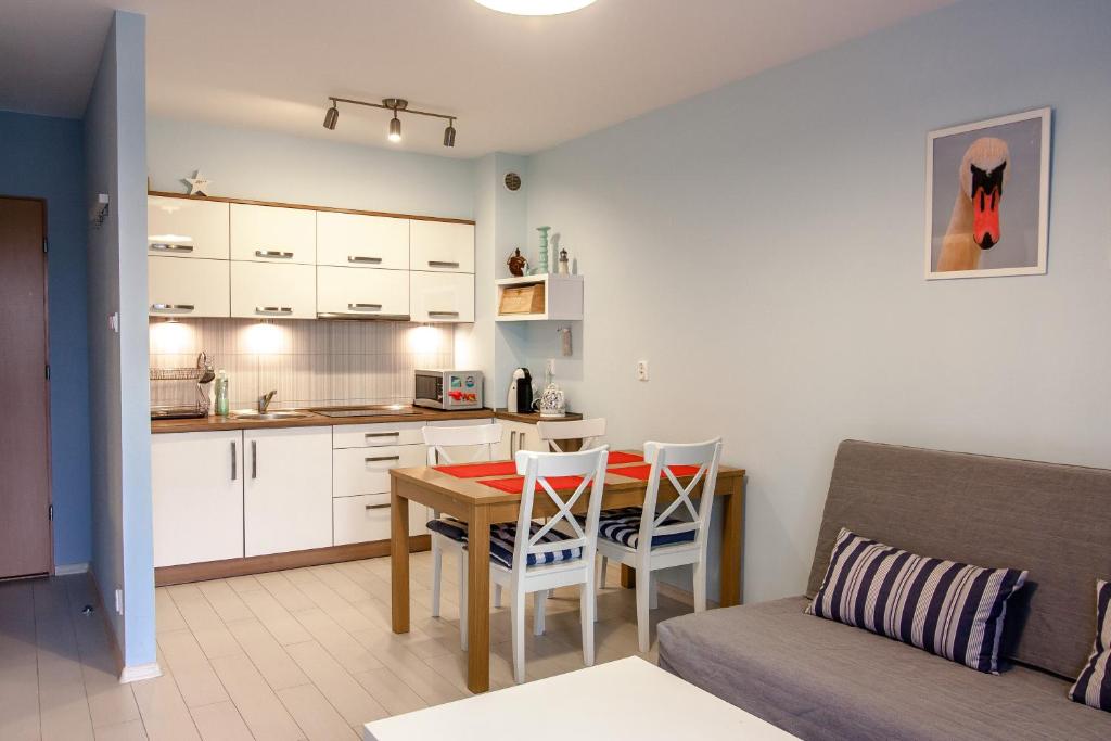 kuchnia oraz salon ze stołem i kanapą w obiekcie Apartament Kapitański Bursztynowe Komnaty w Darłówku