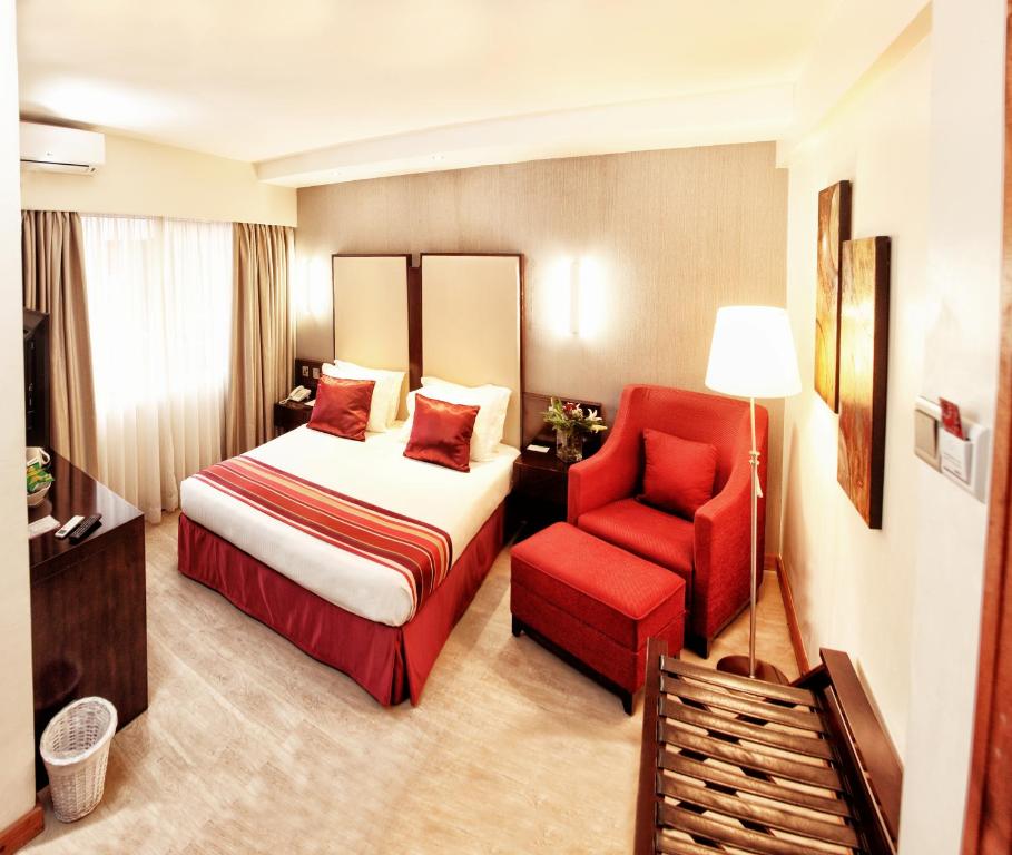 Habitación de hotel con cama y silla roja en The Zehneria Hotel, en Nairobi