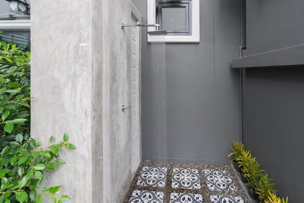 a shower stall with a mosaic floor in a garden at The Besavana Phuket - SHA Extra Plus in Phuket Town
