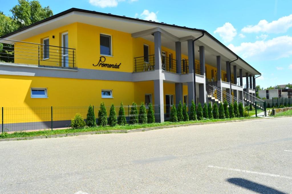 żółty budynek z ulicą przed nim w obiekcie Promenád apartmány w mieście Veľký Meder