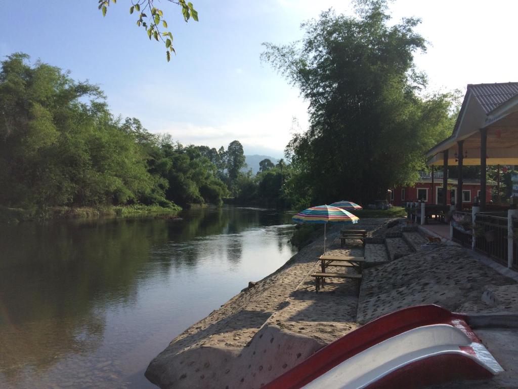 ein Fluss mit einem Boot neben einem Gebäude in der Unterkunft River&Mountain Resort in Nakhon Nayok