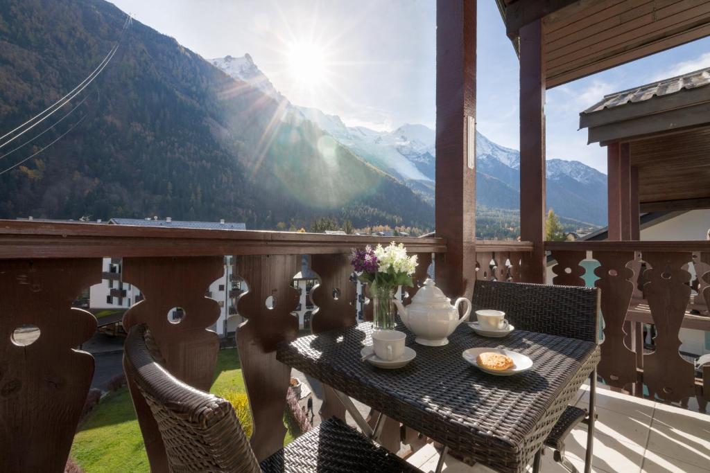 Chamonix Sud - Forclaz 504 Happy Rentals في شامونيه مون بلان: طاولة على شرفة مطلة على الجبال