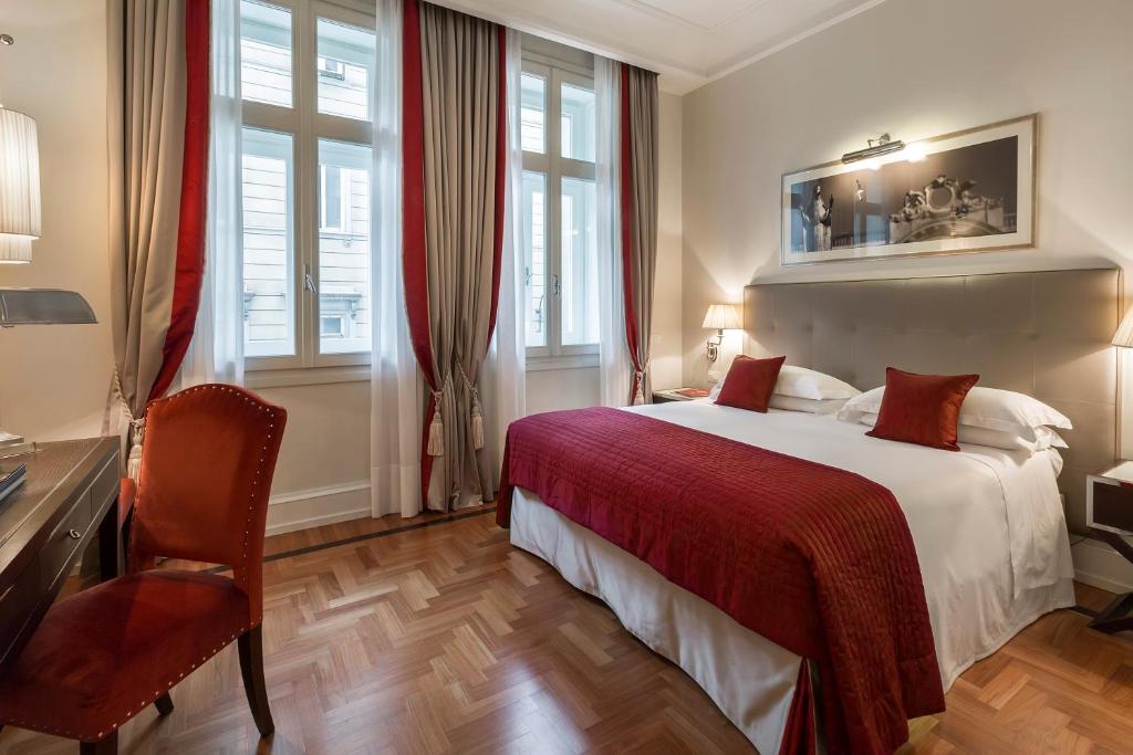 a hotel room with a bed and a desk and window at Savoia Excelsior Palace Trieste - Starhotels Collezione in Trieste